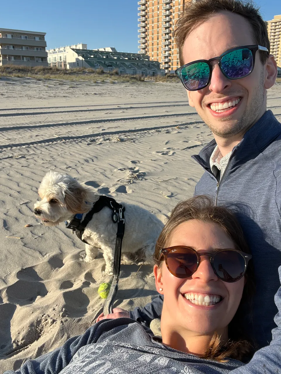 Beach selfie with Loki on his leash in the sand, tennis ball in his mouth.
