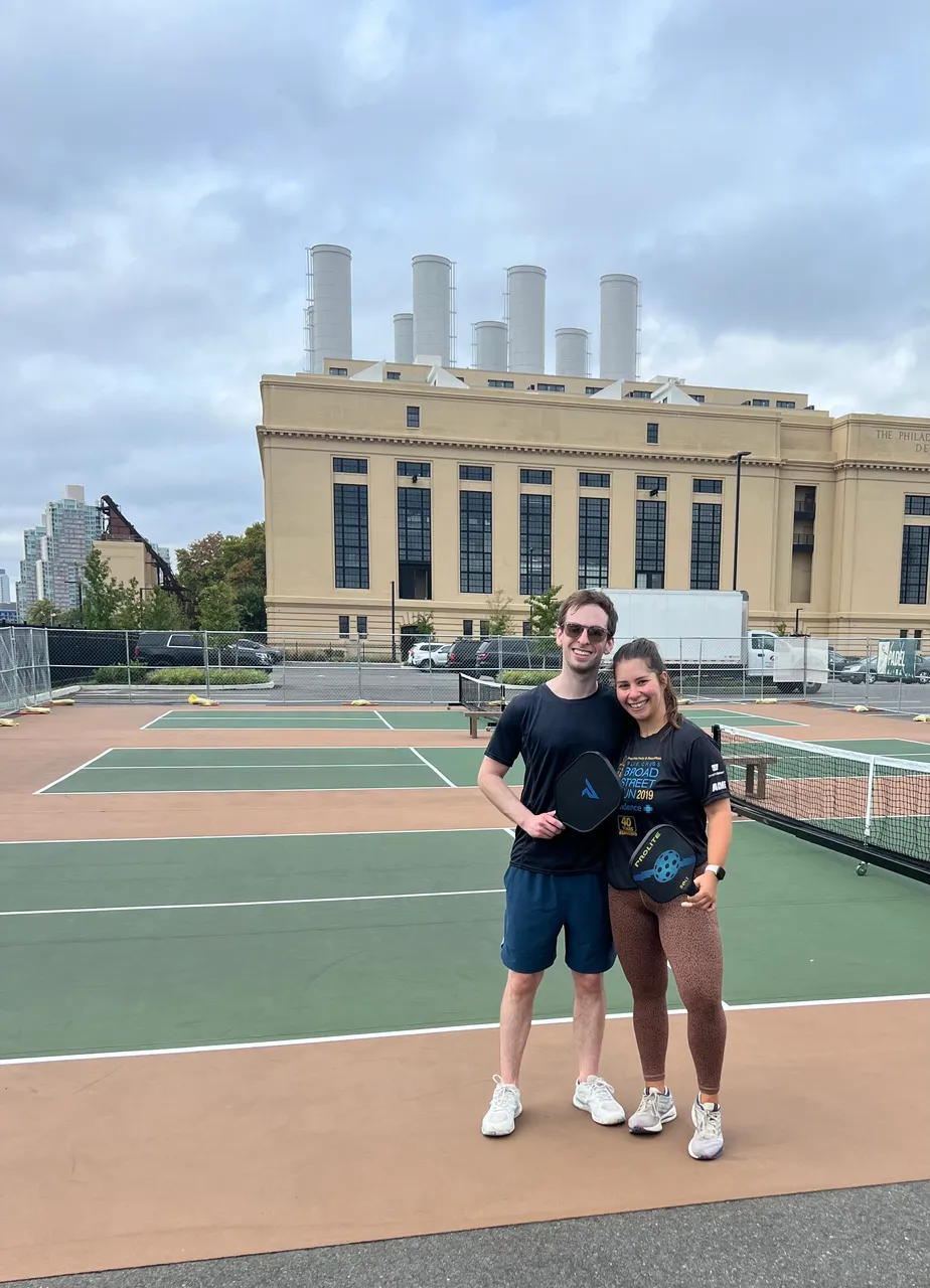 Leah and Justin with pickleball paddles in front of the old Delaware Station power plant.