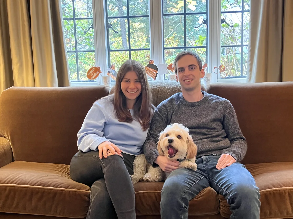 Leah, Justin, and Loki sitting together on the couch by the windows.