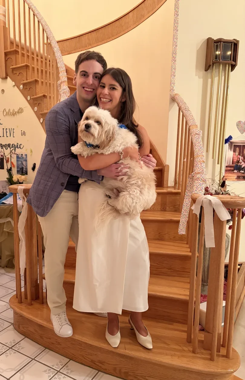 Leah and Justin dressed up on a staircase, holding Loki.