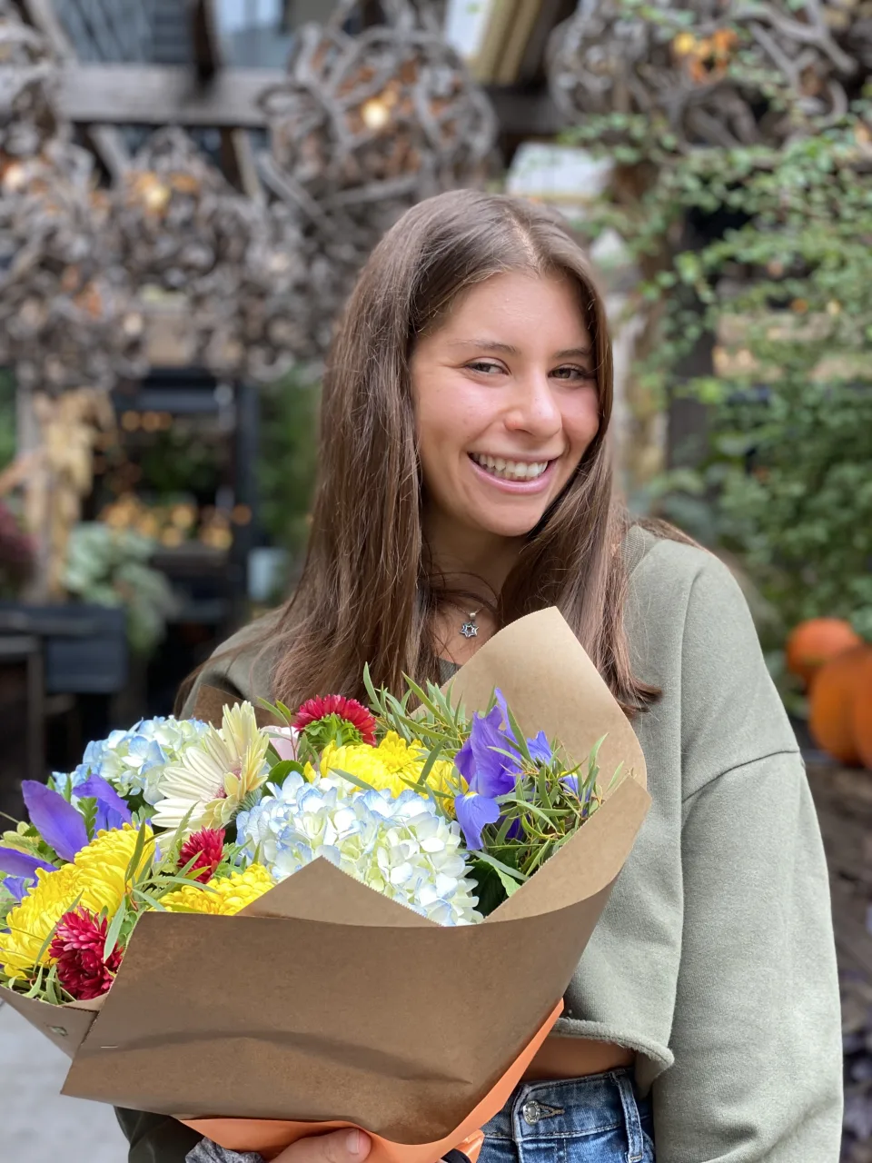 Leah smiling outdoors, holding a big bouquet of flowers.