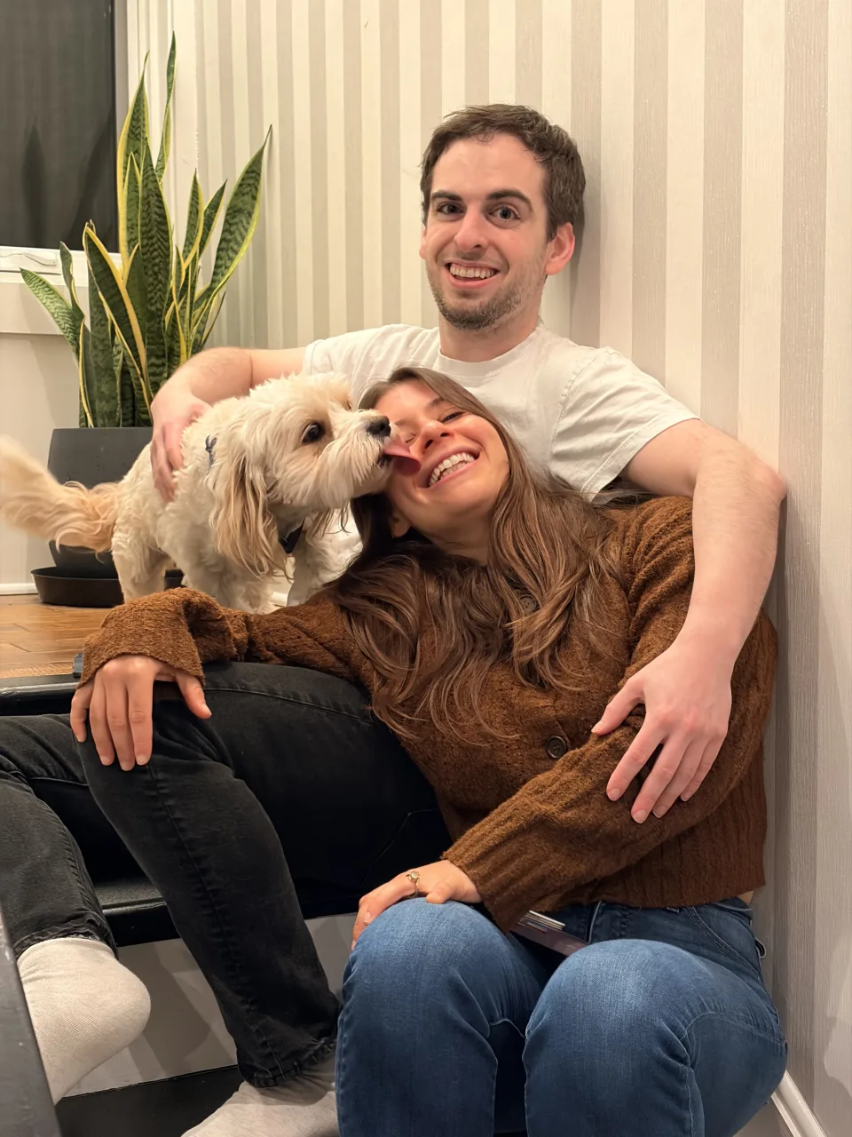 Leah and Justin snuggled on the couch while Loki licks Leah's cheek.