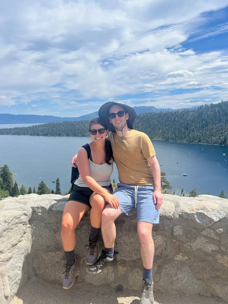 Leah and Justin on a stone overlook above Emerald Bay, Lake Tahoe spread out behind them.