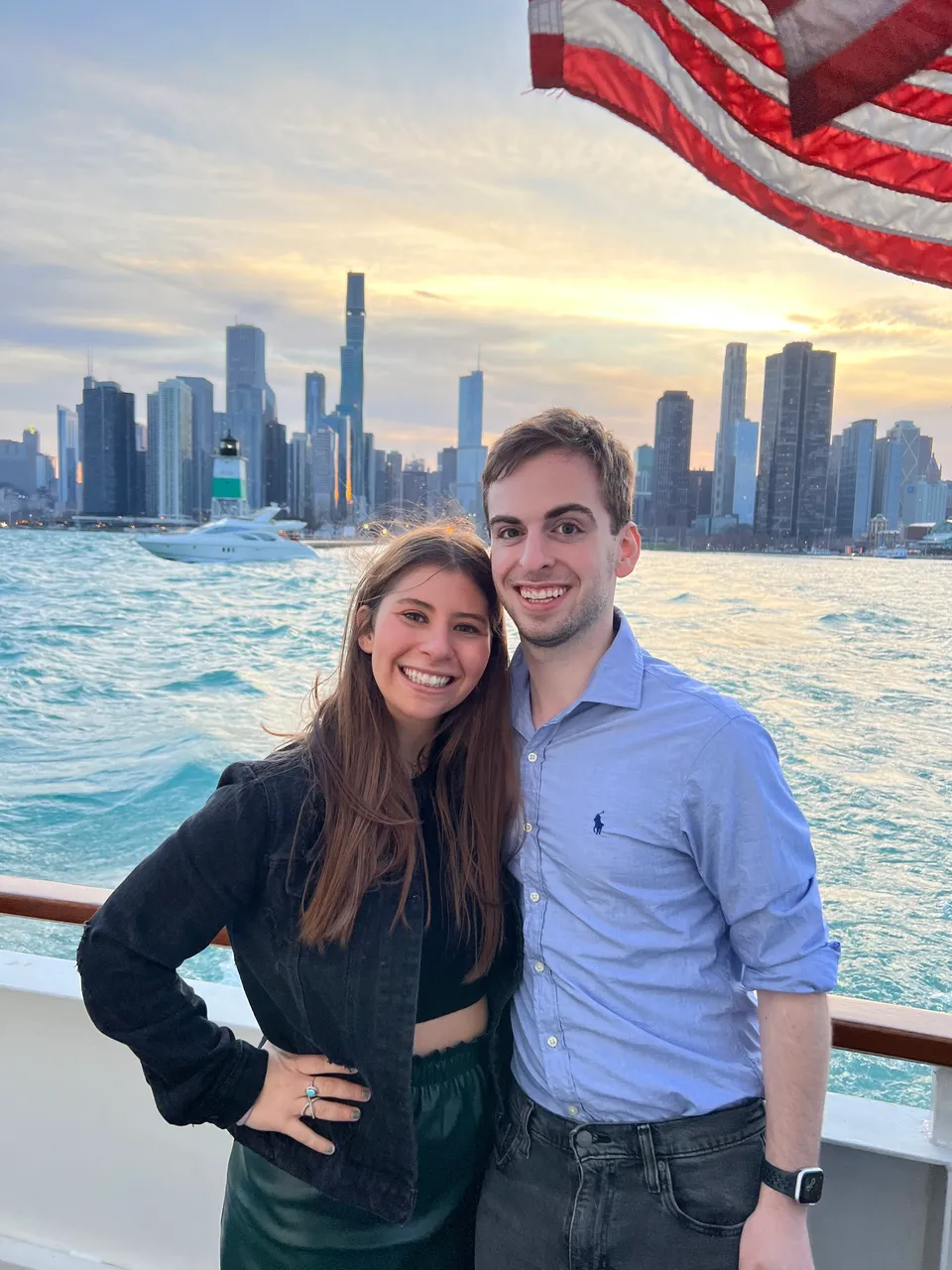 Leah and Justin on a boat on Lake Michigan at golden hour, the Chicago skyline glowing across the water.